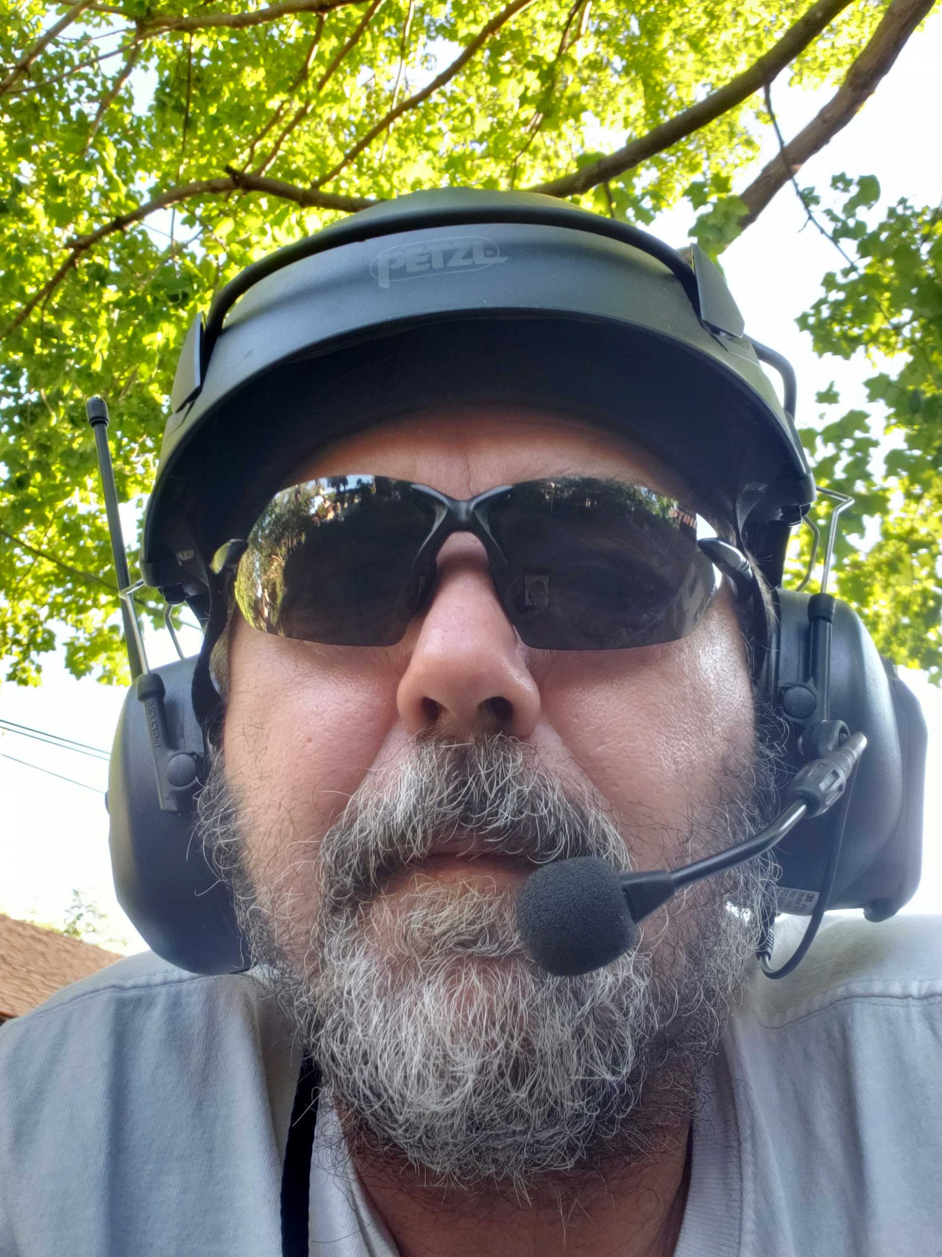Bearded man in helmet, sunglasses, and headset outdoors