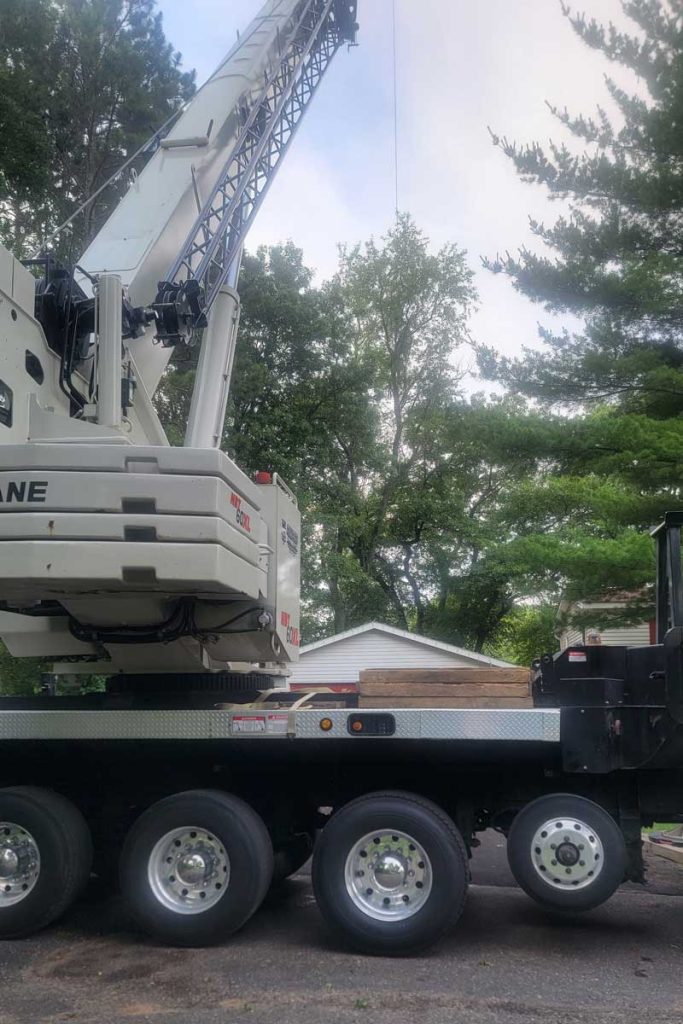 Large mobile crane truck parked near residential trees