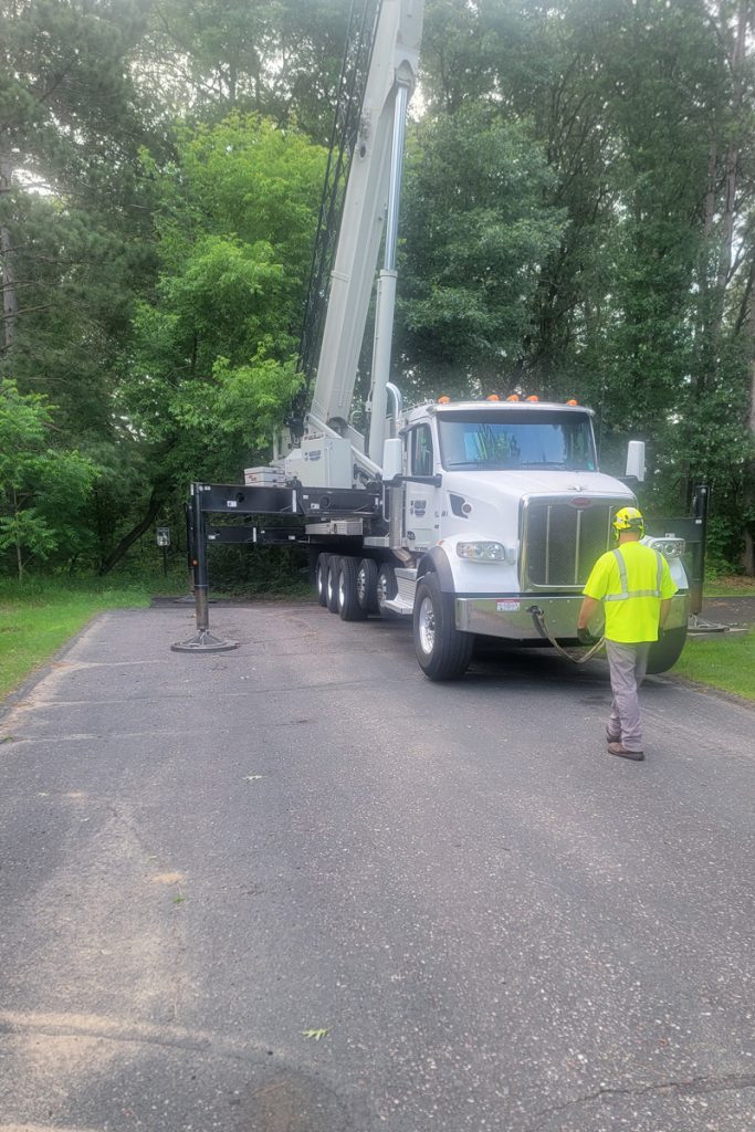 Worker near crane truck with outriggers deployed