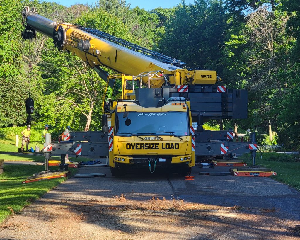 Large yellow crane truck with outriggers extended